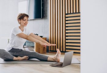 Young woman practising yoga at home on mat