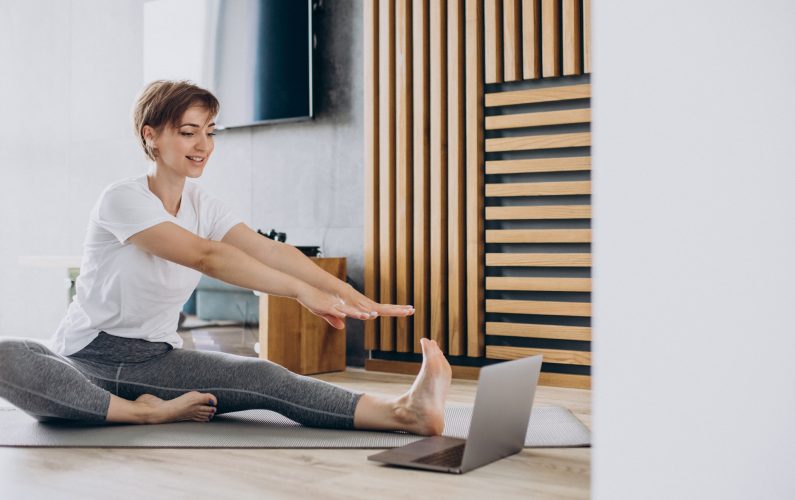 Young woman practising yoga at home on mat