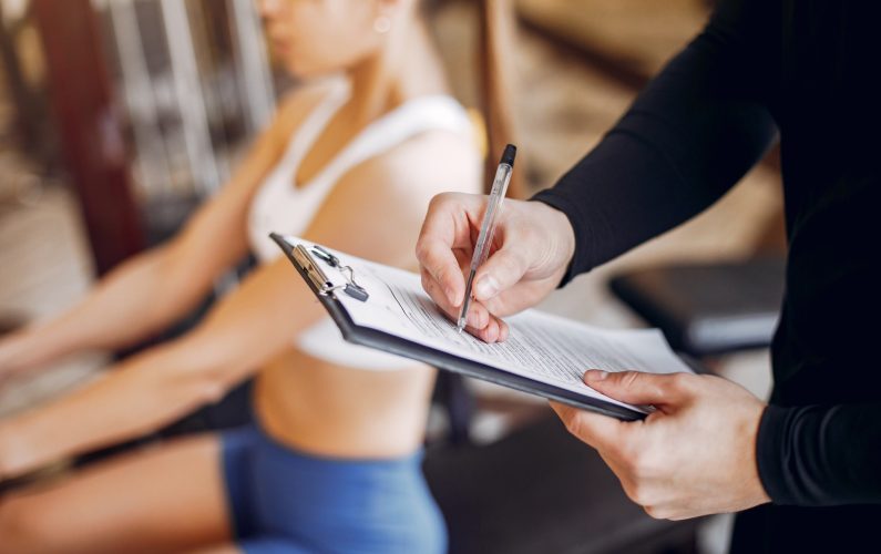 Couple in the gym. A woman performs exercises. Man in a black t-shirt